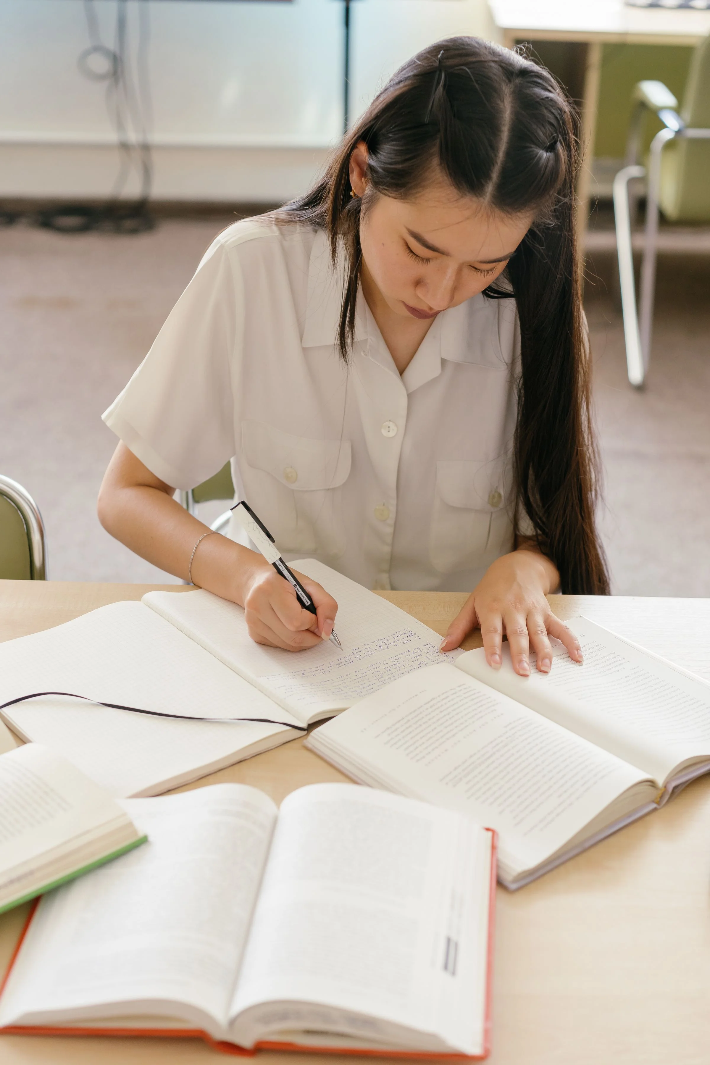 A student writing revision notes beside an open textbook.